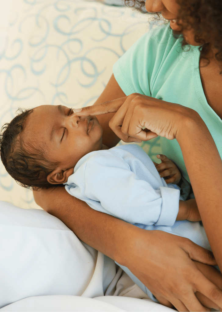 Young mother Black holding her one-month-old newborn baby son carefully and gently in bedroom. Adorable little infant sleep well in warm embrace